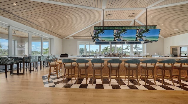 interior space with light wood-type flooring, bar, wood ceiling, and high vaulted ceiling