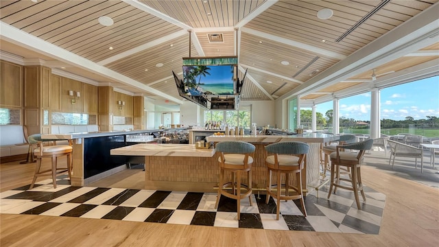 bar with light hardwood / wood-style floors, wood ceiling, light brown cabinetry, and high vaulted ceiling