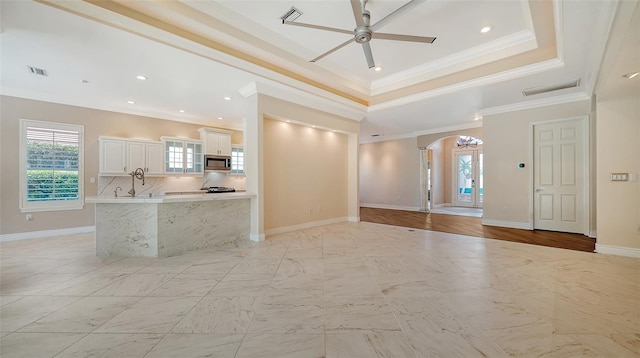 interior space featuring crown molding, ceiling fan, and a raised ceiling