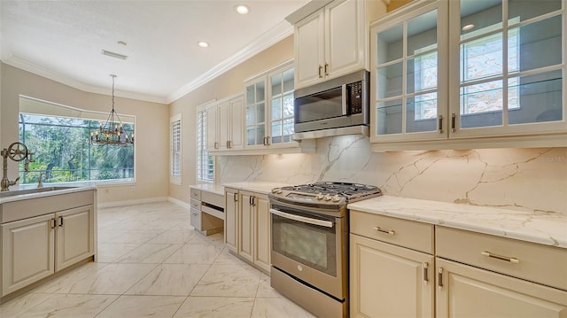 kitchen featuring appliances with stainless steel finishes, hanging light fixtures, backsplash, an inviting chandelier, and ornamental molding