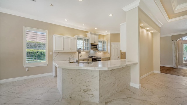 kitchen featuring kitchen peninsula, ornamental molding, stainless steel appliances, and white cabinets