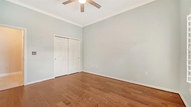 unfurnished bedroom featuring wood-type flooring, a closet, ornamental molding, and ceiling fan