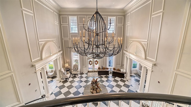 room details featuring crown molding, decorative columns, and an inviting chandelier