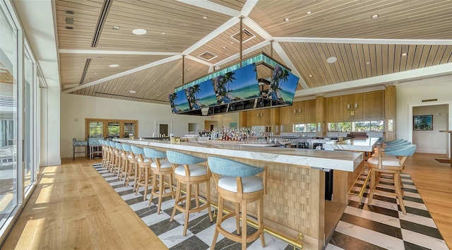 bar with wood ceiling, light hardwood / wood-style floors, high vaulted ceiling, and french doors