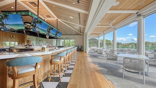 bar with beam ceiling, a water view, light wood-type flooring, and wood ceiling