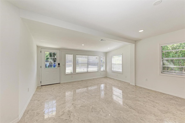 empty room with a wealth of natural light and lofted ceiling