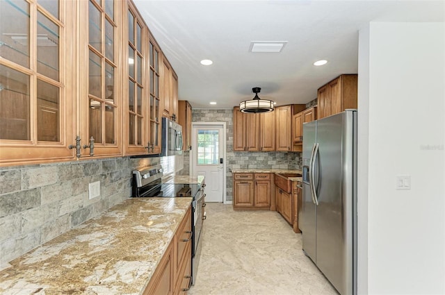 kitchen featuring decorative backsplash, appliances with stainless steel finishes, and light stone counters