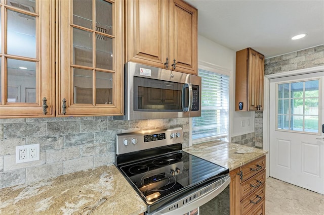 kitchen featuring decorative backsplash, light stone countertops, and stainless steel appliances