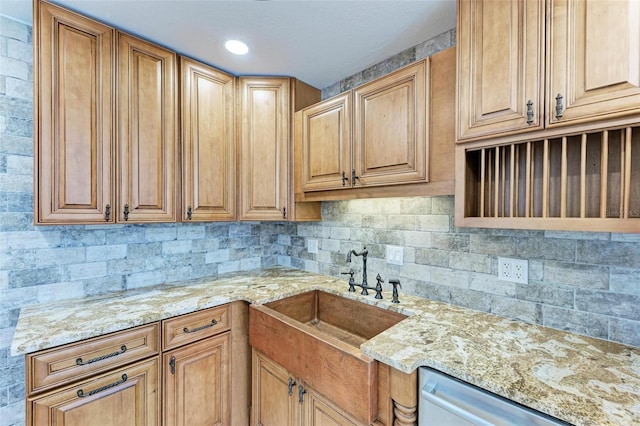 kitchen with decorative backsplash, light stone counters, sink, and dishwasher