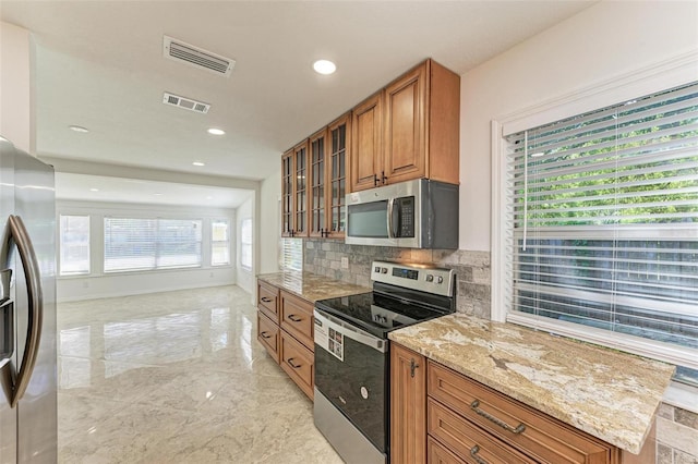 kitchen with light stone counters, stainless steel appliances, and tasteful backsplash