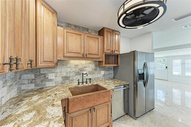 kitchen featuring light stone countertops, sink, tasteful backsplash, a textured ceiling, and appliances with stainless steel finishes