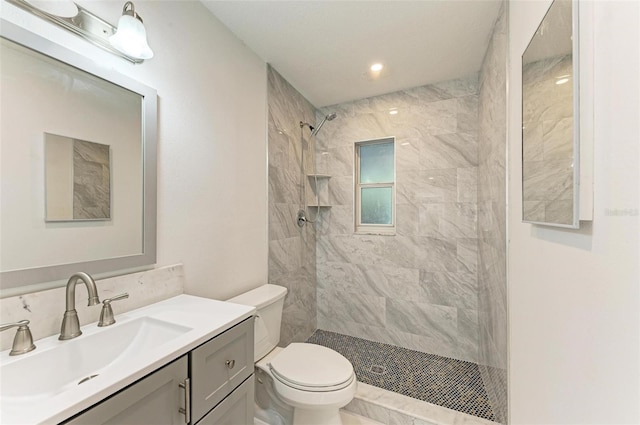 bathroom featuring vanity, toilet, and a tile shower