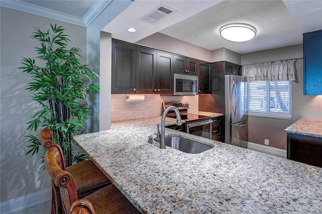 kitchen featuring dark brown cabinetry, light stone counters, sink, kitchen peninsula, and appliances with stainless steel finishes