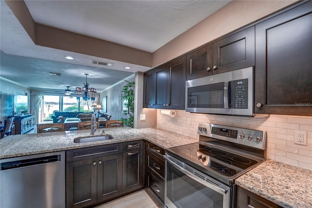 kitchen with appliances with stainless steel finishes, dark brown cabinets, kitchen peninsula, and sink