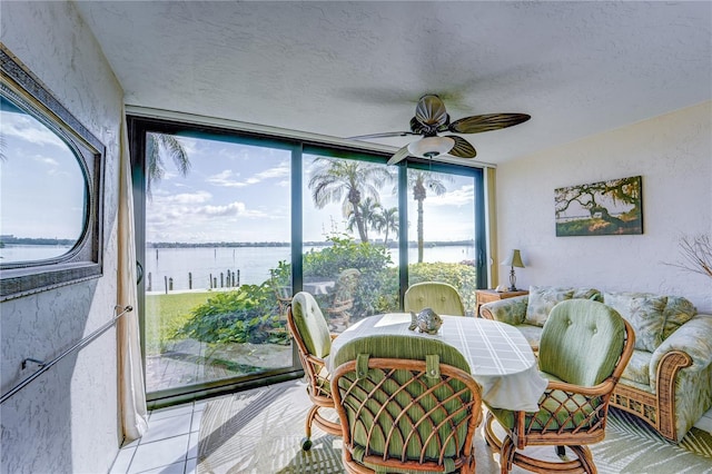 dining room with a textured ceiling, a water view, and ceiling fan