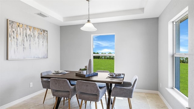 dining space featuring light tile patterned flooring and a raised ceiling