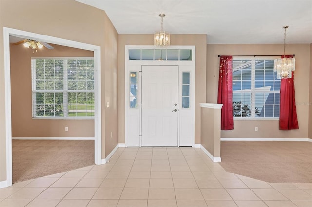 foyer with ceiling fan with notable chandelier and light carpet