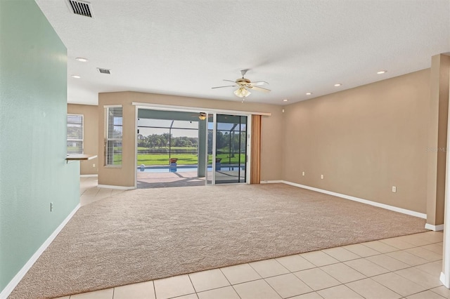 spare room featuring light carpet, ceiling fan, and a textured ceiling