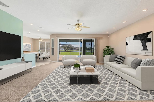 living room with ceiling fan, carpet floors, and a textured ceiling