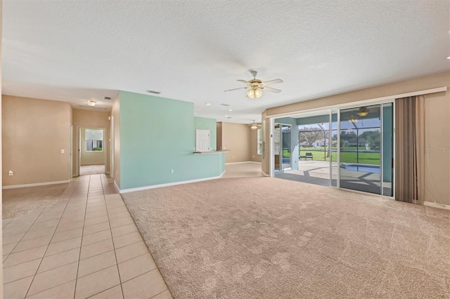 empty room featuring ceiling fan, light tile patterned floors, and a textured ceiling