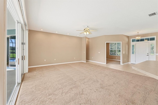 carpeted spare room with a healthy amount of sunlight and ceiling fan with notable chandelier