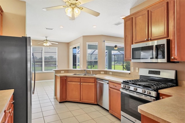 kitchen with sink, kitchen peninsula, stainless steel appliances, light tile patterned floors, and ceiling fan