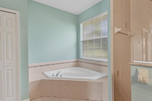 bathroom with tiled tub and tile patterned floors