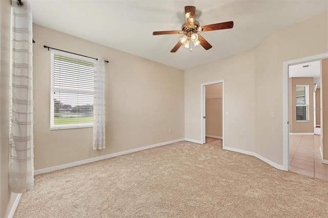 unfurnished bedroom featuring a spacious closet, ceiling fan, light colored carpet, and a closet