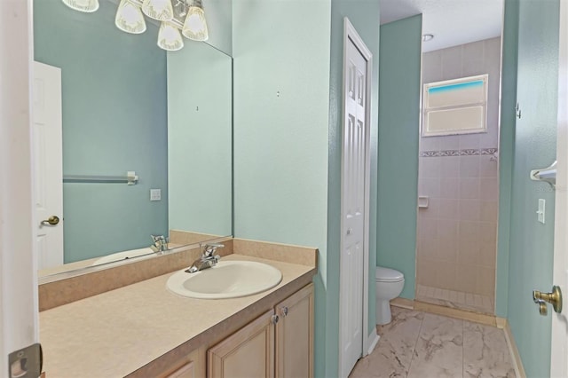 bathroom with vanity, toilet, and tiled shower