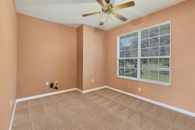 carpeted empty room with ceiling fan, a textured ceiling, and plenty of natural light