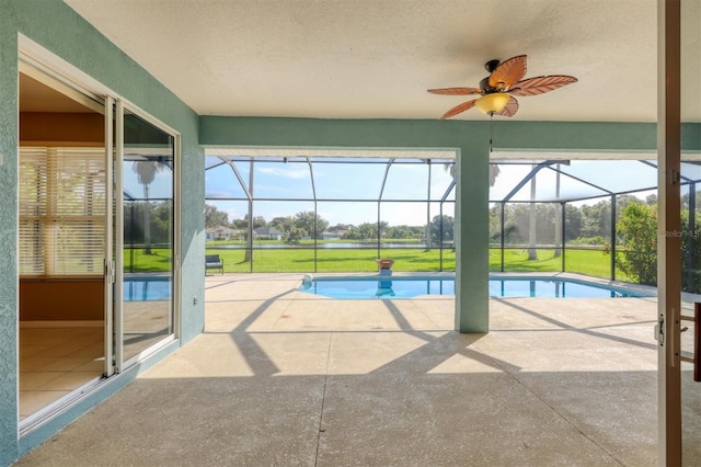 view of swimming pool featuring a lawn, glass enclosure, ceiling fan, and a patio area