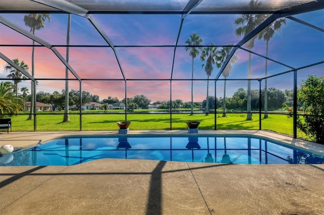 pool at dusk featuring a lawn, a lanai, and a patio area