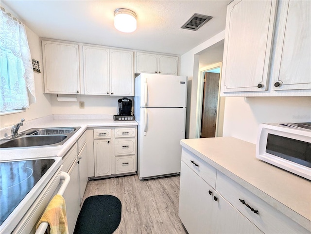 kitchen with light wood-type flooring, white appliances, sink, and white cabinets