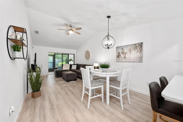 dining space featuring ceiling fan with notable chandelier, vaulted ceiling, and light hardwood / wood-style flooring