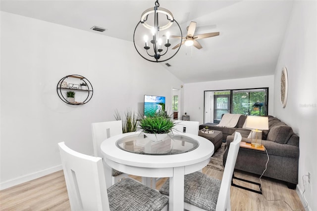 dining space featuring ceiling fan with notable chandelier, light wood-type flooring, and lofted ceiling