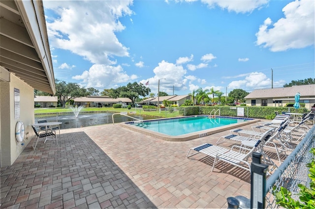 view of swimming pool featuring a water view and a patio area