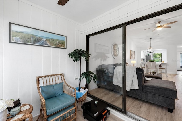 living area featuring ceiling fan with notable chandelier and light hardwood / wood-style flooring