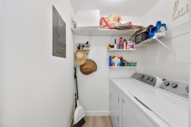 washroom featuring light hardwood / wood-style floors, electric panel, and washing machine and clothes dryer