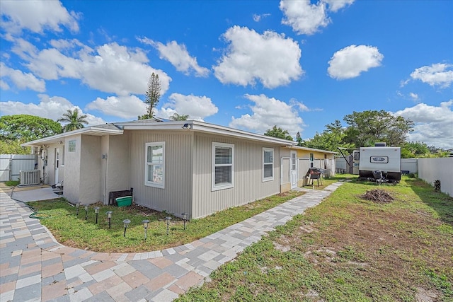 view of side of property featuring cooling unit and a yard