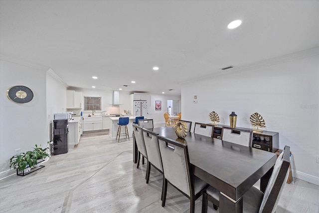 dining area with crown molding and light hardwood / wood-style floors