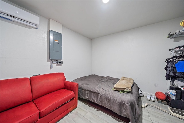 bedroom with light hardwood / wood-style floors, electric panel, and a wall unit AC