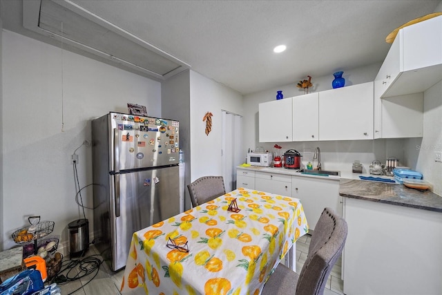 kitchen featuring white cabinets, stainless steel refrigerator, and sink