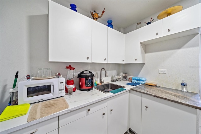 kitchen featuring white cabinetry and sink