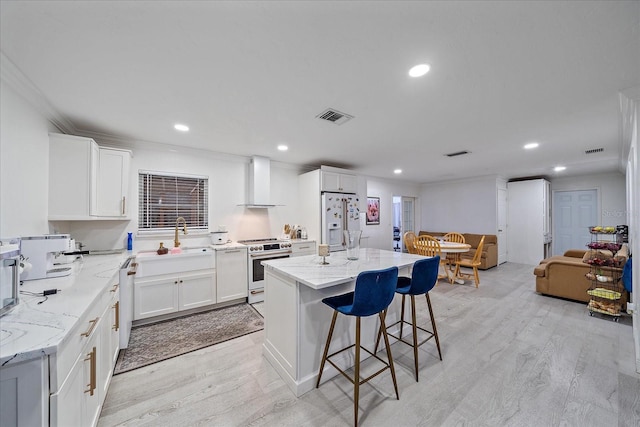 kitchen featuring light hardwood / wood-style floors, stainless steel range, white refrigerator with ice dispenser, and a kitchen island