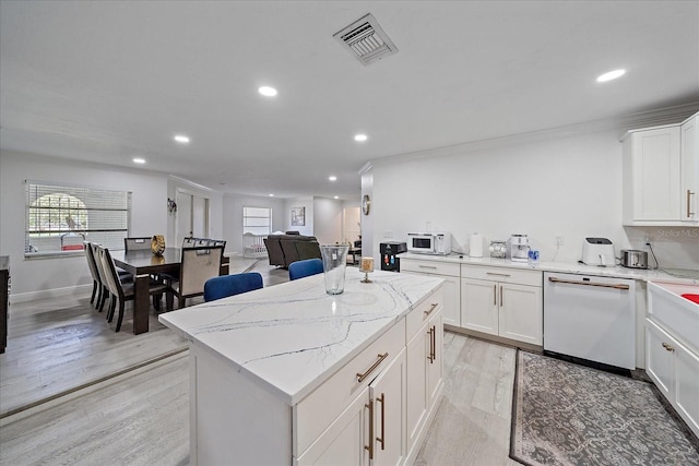 kitchen with white cabinets, a kitchen island, light hardwood / wood-style flooring, white appliances, and light stone countertops