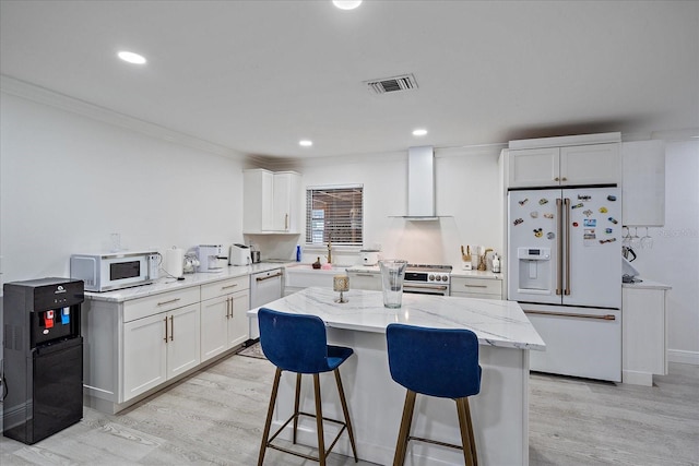 kitchen featuring wall chimney exhaust hood, white cabinets, white appliances, and light wood-type flooring