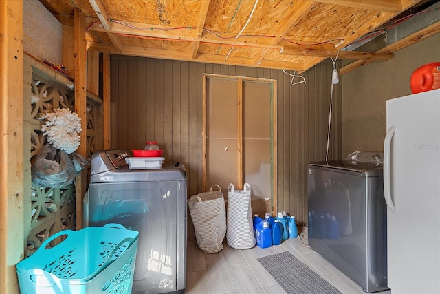 clothes washing area featuring washer and clothes dryer and wooden walls