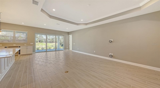 unfurnished living room featuring a tray ceiling, crown molding, and light wood-type flooring