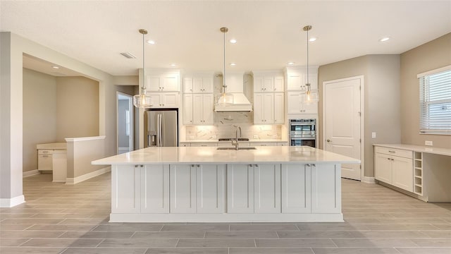 kitchen featuring pendant lighting, a kitchen island with sink, premium range hood, and appliances with stainless steel finishes