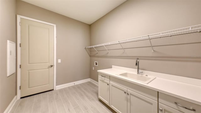 clothes washing area featuring cabinets, hookup for a washing machine, light hardwood / wood-style floors, and sink